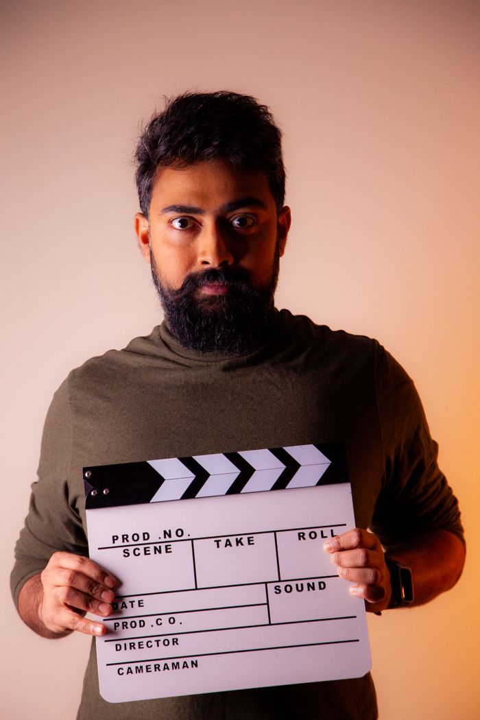 services-01 Studio portrait of a man with beard holding a clapperboard, highlighting filmmaking theme.