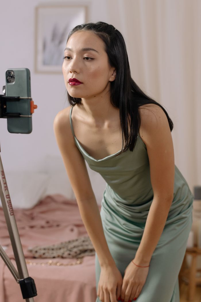 ours-journey An Asian woman in a dress streaming live indoors using a cellphone.